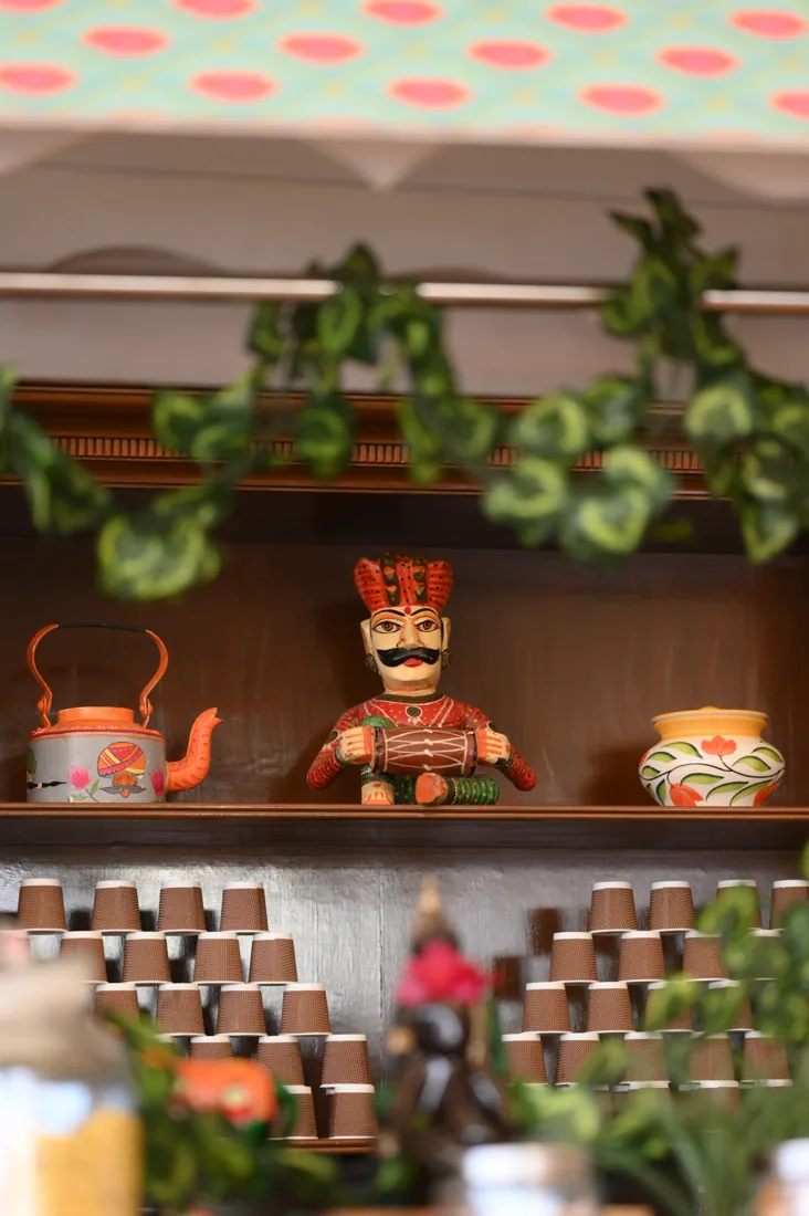 Chapas cafe shelf with Rajasthani figurines, painted kettle and stacked kulhads